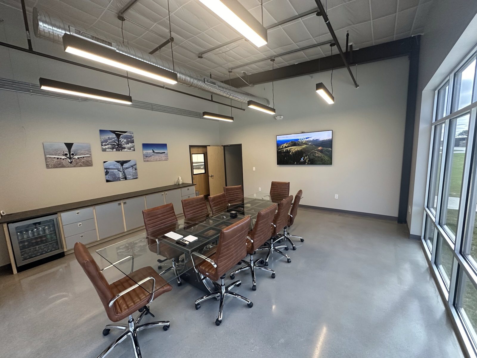 The conference room with a glass table, leather chairs and aircraft photographs on the wall, looking out to the ramp